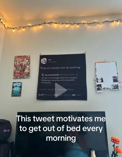 image of a framed quote-tweet on a bedroom wall. the quoted tweet says "we don't talk enough about how stressful halloween costumes are for the adhd community", replied with: "omg you people cant do anything". over the photo, there's an overlaid text saying "this tweet motivates me to get out of bed every morning"